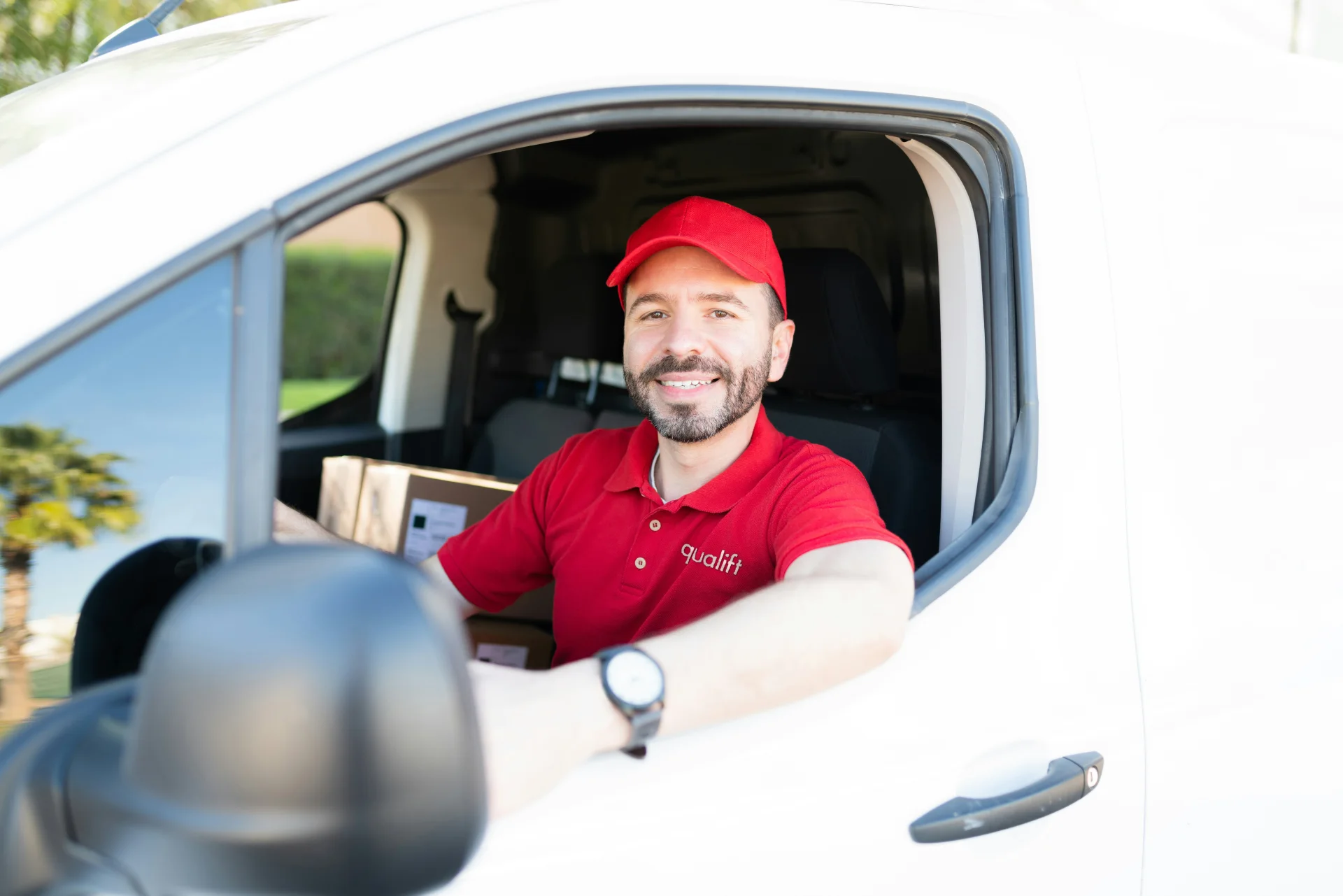 Chofer de Qualift con polo bordado de la marca al volante de una unidad de reparto
