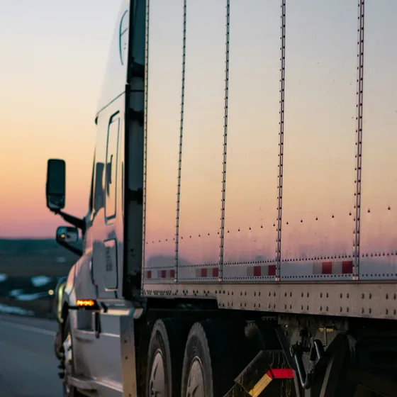 Tractocamión con caja seca circulando en carretera al atardecer